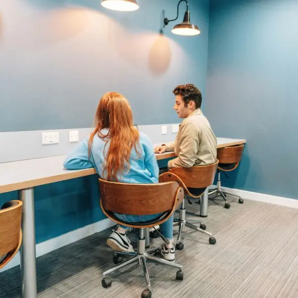 Two students sat at a long desk working together.